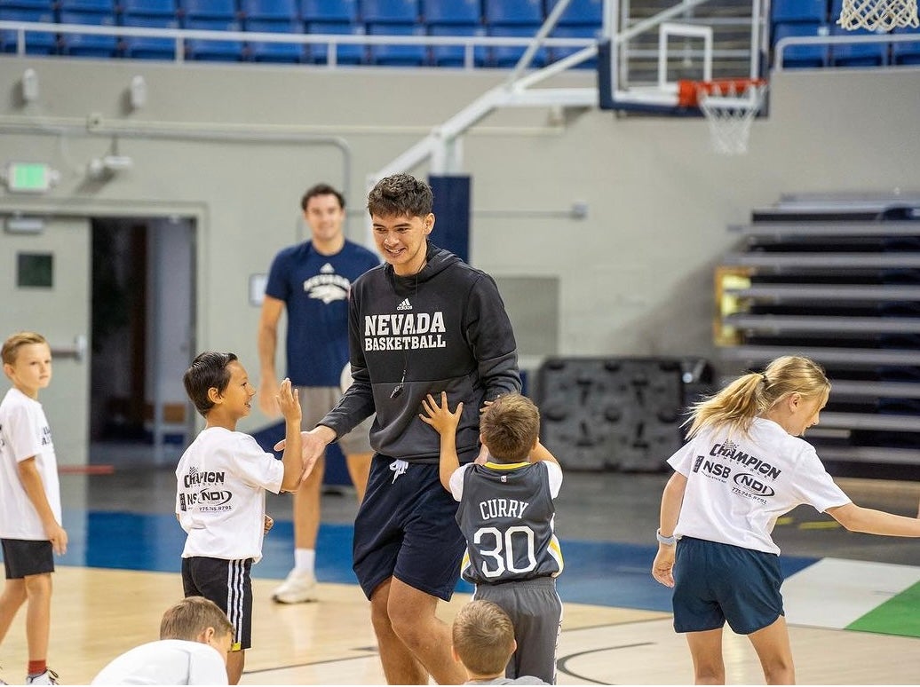 Basketball player high-fiving children at clinic